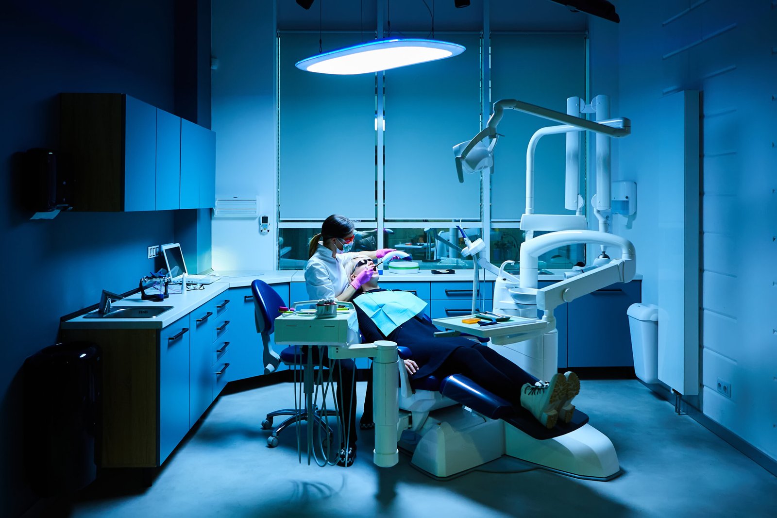 Female dentist examining and treating patient teeth in dental clinic